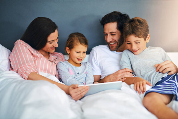 Коли ми маємо одне одного, ми маємо все. молода сім'я використовує планшет під час охолодження в ліжку разом вдома
 - Фото, зображення