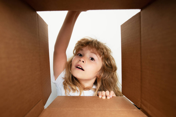Cheerful cute child opening a present. Cardboard boxes, parcels. Delivery service concept. Kid opening package - Photo, Image
