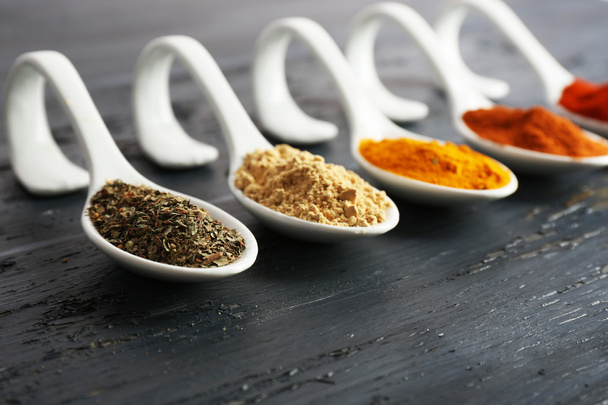 Different kinds of spices in spoons on wooden background - Fotó, kép