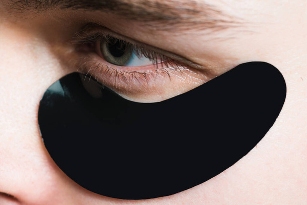 Skin care. Black pearl extract. Minimizes puffiness and reduce dark circles. Eye patches for men. Man with black eye patches close up. Metrosexual concept. Focused treatments for under eye area. - Photo, Image