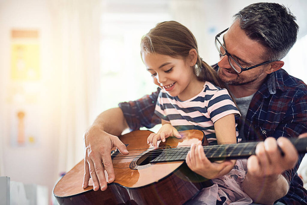 Learning, guitar and girl, man with smile for music or bonding or love or play at house. Happiness, teaching and kid, father with acoustic or musical instrument for fun or education at family home - Фото, изображение