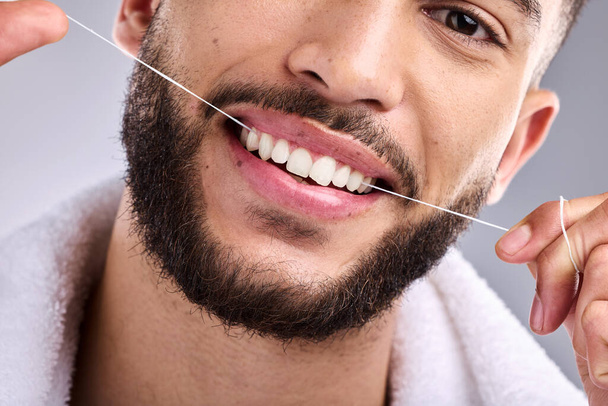 Face, man and flossing teeth for dental health in studio isolated on a white background. Portrait, floss and male model cleaning tooth for oral wellness, hygiene and healthy gums for fresh breath - Foto, Imagem