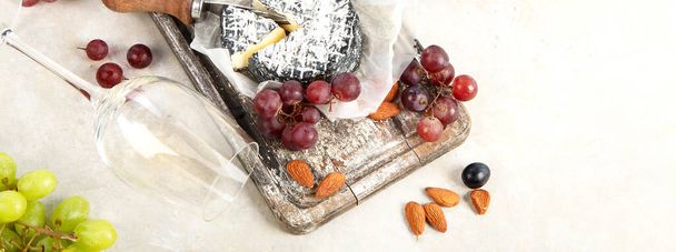 Pink and red wine served with cheeses, nuts, grapes and glasses of wine. Delicious food wine snacks assorted served on boards. Flat lay on a white background. Panorama. - Photo, image