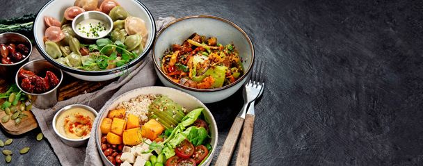Healthy vegetarian and vegan dumplings and Buddha Bowls with vitamins, antioxidants, protein on dark background. Top view. Panorama with copy space. - Фото, изображение