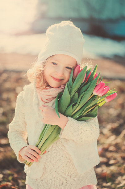Spring vintage tones portrait of happy child girl with tulips bouquet for woman's day - Fotoğraf, Görsel