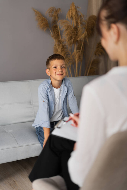 Esikoululainen poika vierailee psykoterapeutilla, nainen ja lapsi puhuvat ongelmasta, psykoterapia istunto virassa, lapsi hymyilee psykologi. Kopioi tila - Valokuva, kuva