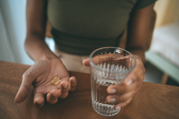 アフリカ系アメリカ人の女の子が手に錠剤や錠剤を保持し、水のガラスを閉じます。薬、ビタミンや栄養補助食品. - 写真・画像
