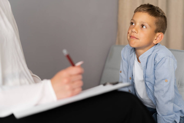 Psicólogo infantil profesional trabajando con un niño pequeño en una oficina luminosa. Primer plano - Foto, Imagen