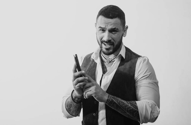 Masculinity concept. Portrait of sexy handsome fashion man model with confident expression, dressed in elegant white shirt, looks at camera, having a phone talk. Brutal bearded boy with tattoo - Photo, Image