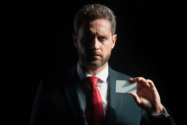 Confident businessman with credit card. Middle-age business man in formalwear suit isolated on black - Foto, imagen