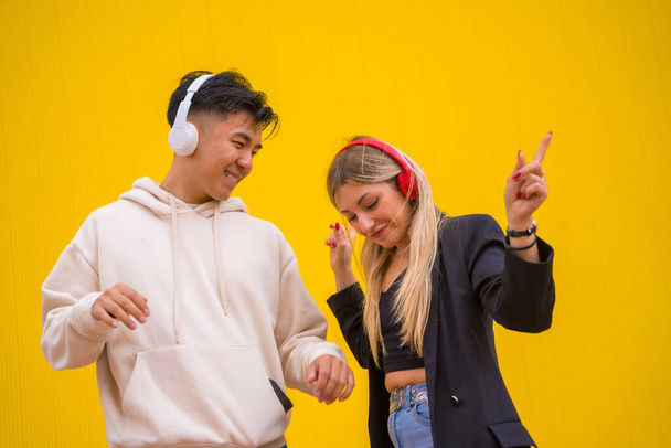 Multiethnic couple of Asian man and Caucasian woman on a yellow background, dancing bachata - Fotó, kép