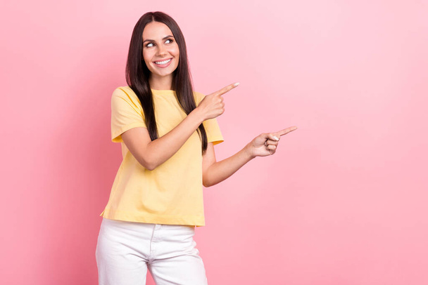 Photo attractive promoter woman direct fingers empty space banner ads information wear yellow shirt isolated pink color background. - Photo, Image