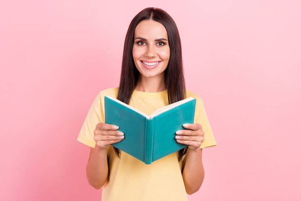 Photo de dame adorable brillant porter t-shirt jaune sourire lecture intéressant livre isolé fond de couleur rose. - Photo, image