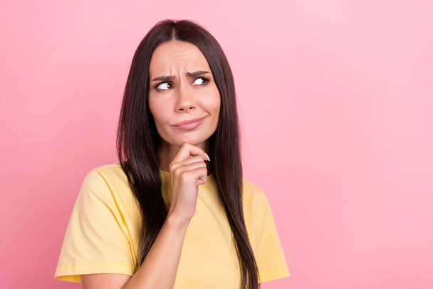 Photo of doubtful suspicious lady wear yellow t-shirt arm chin looking empty space isolated pink color background. - Foto, afbeelding