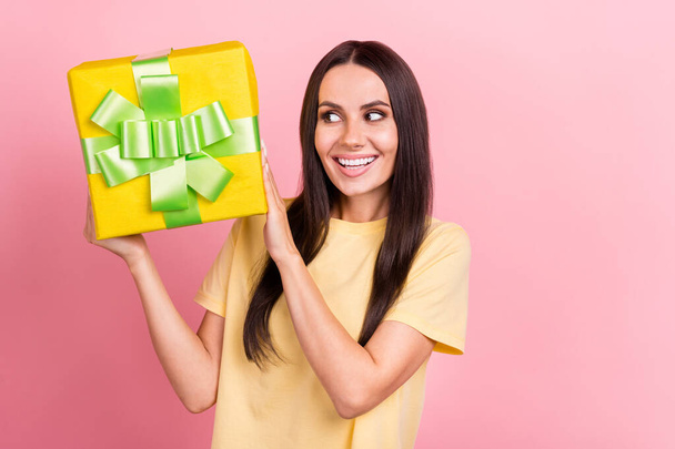 Photo of dreamy tricky lady wear yellow t-shirt guessing inside gift box isolated pink color background. - Foto, Imagem