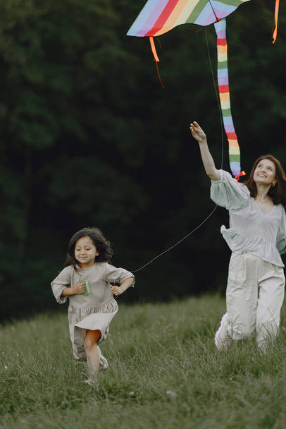 Laughing woman and little cute child baby in a park. Family play with colorful kite in park. - Photo, image