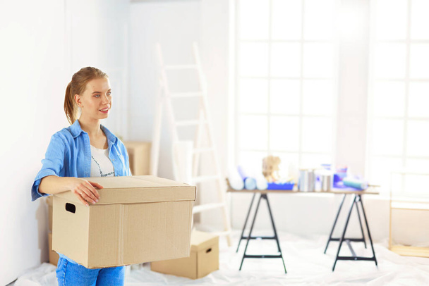 Young woman moving house to new home holding cardboard boxes . - Foto, imagen