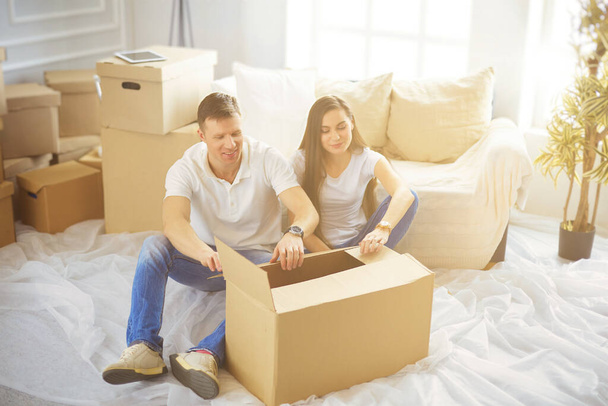 Happy young couple unpacking or packing boxes and moving into a new home. - Photo, image
