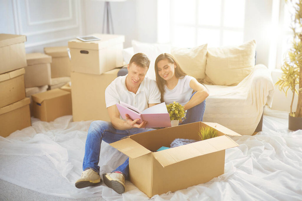 Happy young couple unpacking or packing boxes and moving into a new home. - Photo, Image