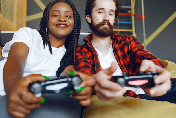 Black girl in a white t-shirt. Couple playing a video games. People use a joystick - Foto, Imagen