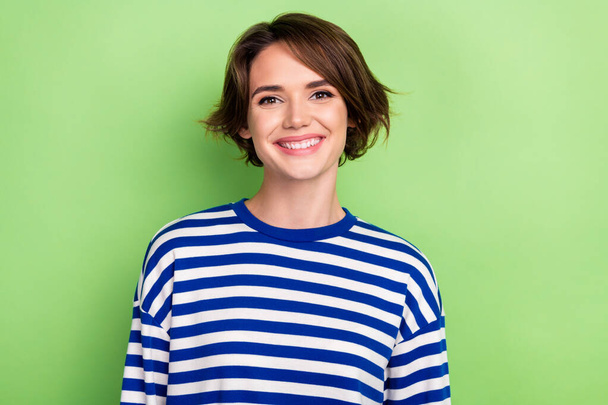 Foto van charmante schattige jonge dame stralen glimlachende camera dragen gestreept zeiler shirt geïsoleerde groene kleur achtergrond. - Foto, afbeelding