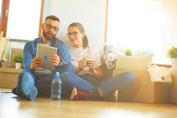 Happy couple planning decoration when moving home sitting on the floor. - Foto, Bild