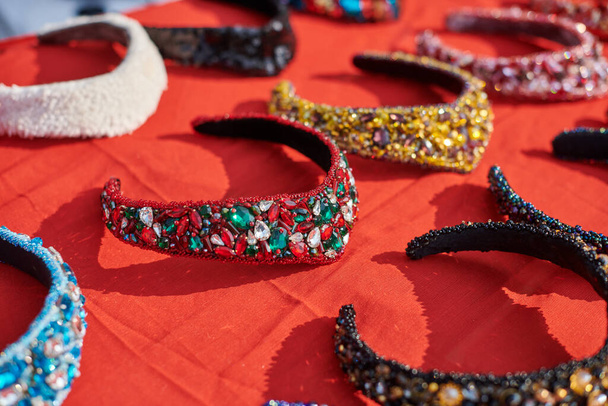 Exposição de headwear tradicional russa diferente, headbands decorativos jóias coloridas decoradas na mesa vermelha, coberturas para a cabeça russas frisado jóias espumantes, bela bandana russa - Foto, Imagem