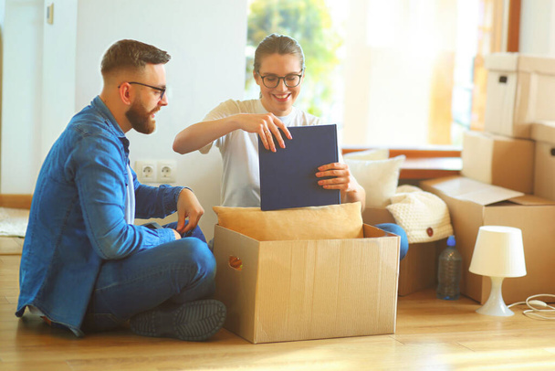 Cute couple unpacking cardboard boxes in their new home. - Foto, imagen