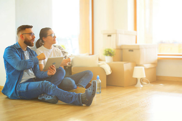 Happy couple planning decoration when moving home sitting on the floor. - Photo, image