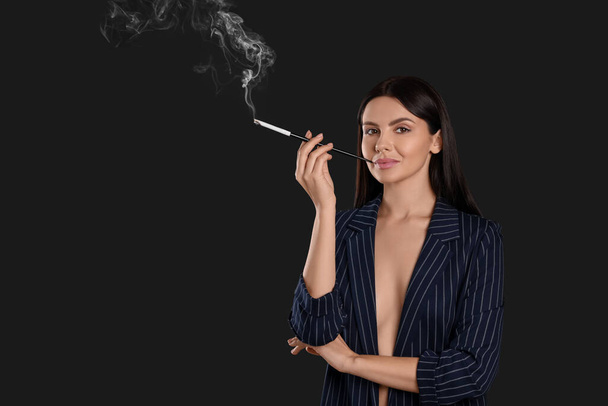 Woman using long cigarette holder for smoking on black background, space for text - Фото, изображение