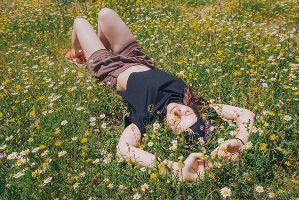 Baharda çimenler ve çiçeklerle yatıp uyuyan kız. - Fotoğraf, Görsel