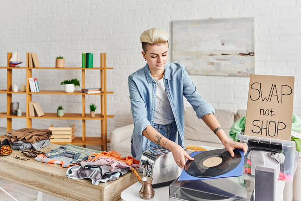 collaborative consumption, smiling tattooed woman holding vinyl disc near record player, electric toaster, cezve, clothes and swap not shop card, sustainable living and circular economy concept - Photo, Image