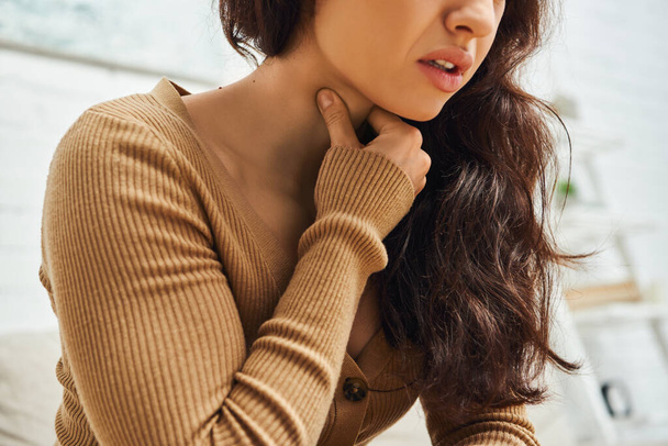 Cropped view of young brunette woman in brown jumper suffering from neck pain during self-massage at home, self-care ritual and holistic healing concept, balancing energy, tension relief - Photo, Image