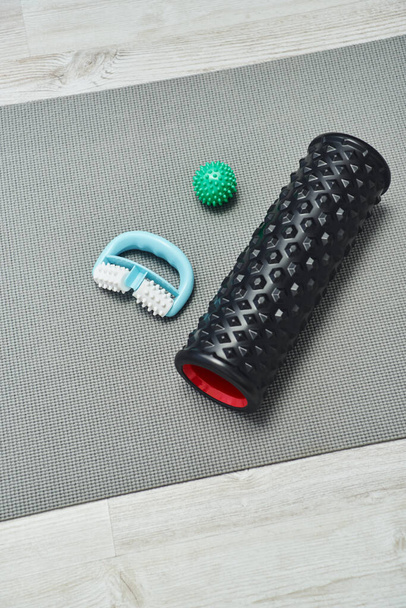Top view of handle and roller massagers near handle ball lying on fitness mat on floor at home, natural health practices and home-based massage concept, health and relaxation, beauty routine  - Photo, Image