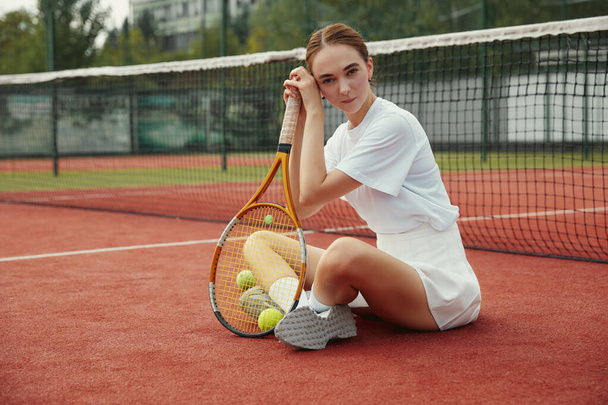 A Woman resting after play tennis on carpet court outdoors. Weekend and Sunday activity for recreation. Sports active game with friends. Tennis player in action. Tennis match. Active leisure game. - Foto, Imagem