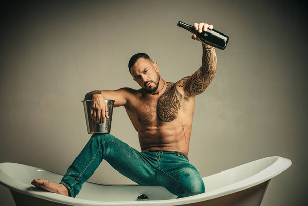 Man on sexy party with bottle of champagne on grey background - Foto, Bild