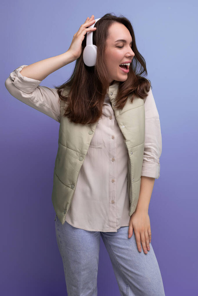 positive 30s lady with wireless headphones is having a blast on studio background. - Photo, Image