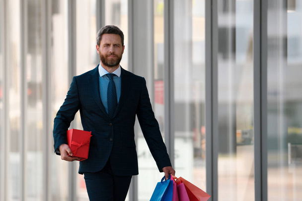 Бізнесмен тримає сумки для покупок і ходить у магазині. Шопінг і оплата. концепція шопінгу
 - Фото, зображення