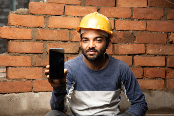 Indiaas bouwvakker of dagarbeider met mobiele telefoon ter plaatse - Foto, afbeelding