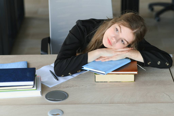 A cute schoolgirl is sitting at a desk at school. The concept of schooling - Fotografie, Obrázek