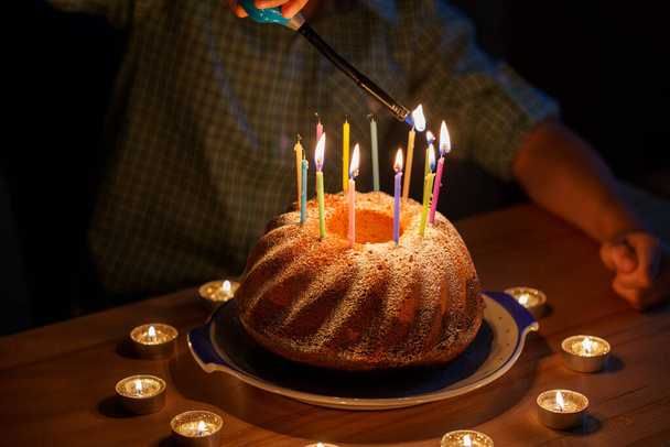 Gelukkige blonde kleine jongen viert zijn verjaardag. Peuter die kaarsen blaast op zelfgebakken taart, binnen. Verjaardagsfeest voor schoolkinderen, familiefeest. - Foto, afbeelding