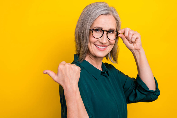 Profile photo of cheerful person arm touch eyewear indicate thumb finger empty space isolated on yellow color background. - Foto, imagen