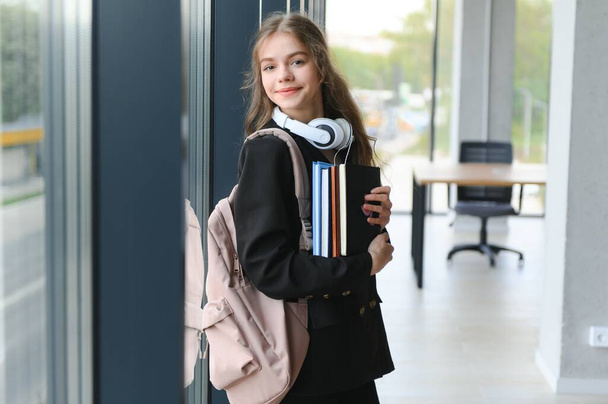 Portrait of a schoolgirl standing in the classroom with a book in her hands - Fotografie, Obrázek