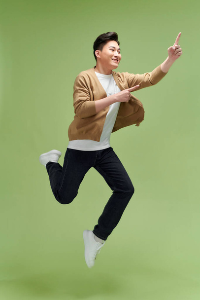Plná délka vzrušený mladý muž skok vysoký ukazováček stranou na pracovní ploše izolované  - Fotografie, Obrázek
