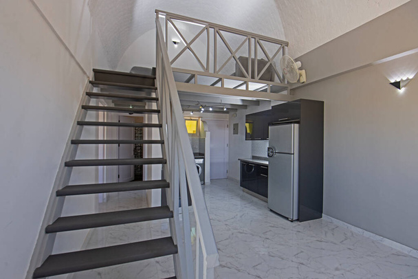 Интерьер декора показывает современную кухню и бытовую технику в роскошном двухуровневом салоне с деревянной лестницей - Фото, изображение