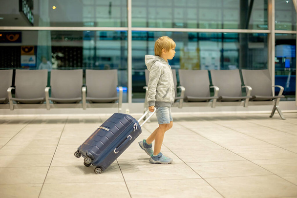 Children with suitcases at airport, walking at night together, waiting for a flight - Fotó, kép