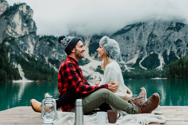 Beautiful couple of young adults visiting an alpine lake at Braies, Italy - Tourists with hiking outfit having fun on vacation during autumn foliage - Concepts about travel, lifestyle and wanderlust - Photo, Image