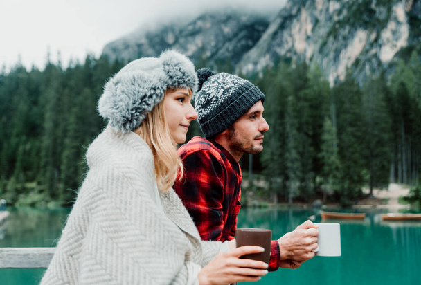 Bacio romantico di una coppia di adulti in visita ad un lago alpino a Braies - Turista innamorato che beve cioccolata calda sulle montagne autunnali - Concetto di coppia, passione e viaggio - Foto, immagini