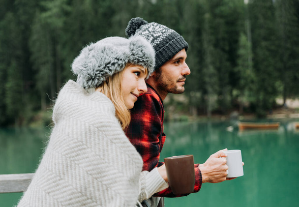 Beso romántico de un par de adultos que visitan un lago alpino en Braies Italia - Turista enamorado de beber chocolate caliente en las montañas de otoño - Pareja, vagabundeo y concepto de viaje - Foto, imagen