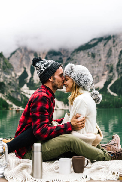 Ρομαντικό φιλί ενός ζευγαριού ενηλίκων που επισκέπτονται μια αλπική λίμνη στο Braies Ιταλία. Tourist στην αγάπη περνούν στιγμές αγάπης μαζί το φθινόπωρο φθινόπωρο. Ζευγάρι, περιπλάνηση και ταξιδιωτική έννοια. - Φωτογραφία, εικόνα